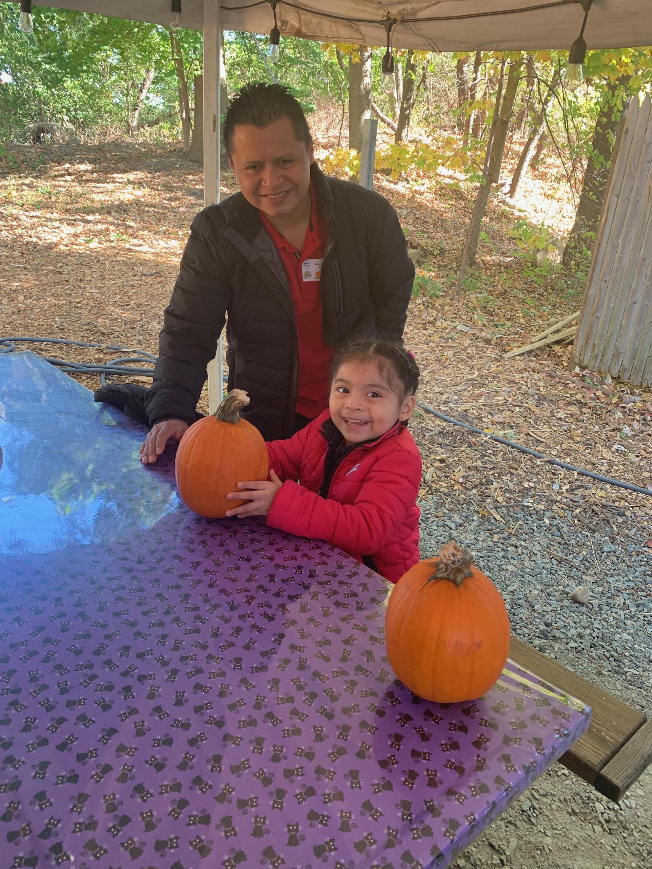 Dad and happy daughter with a medium sized pumpkin