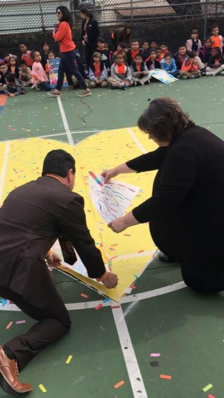 Principal Celebrano and Asst. Supt. Perez placing pieces of a floor puzzle on schoolyard floor