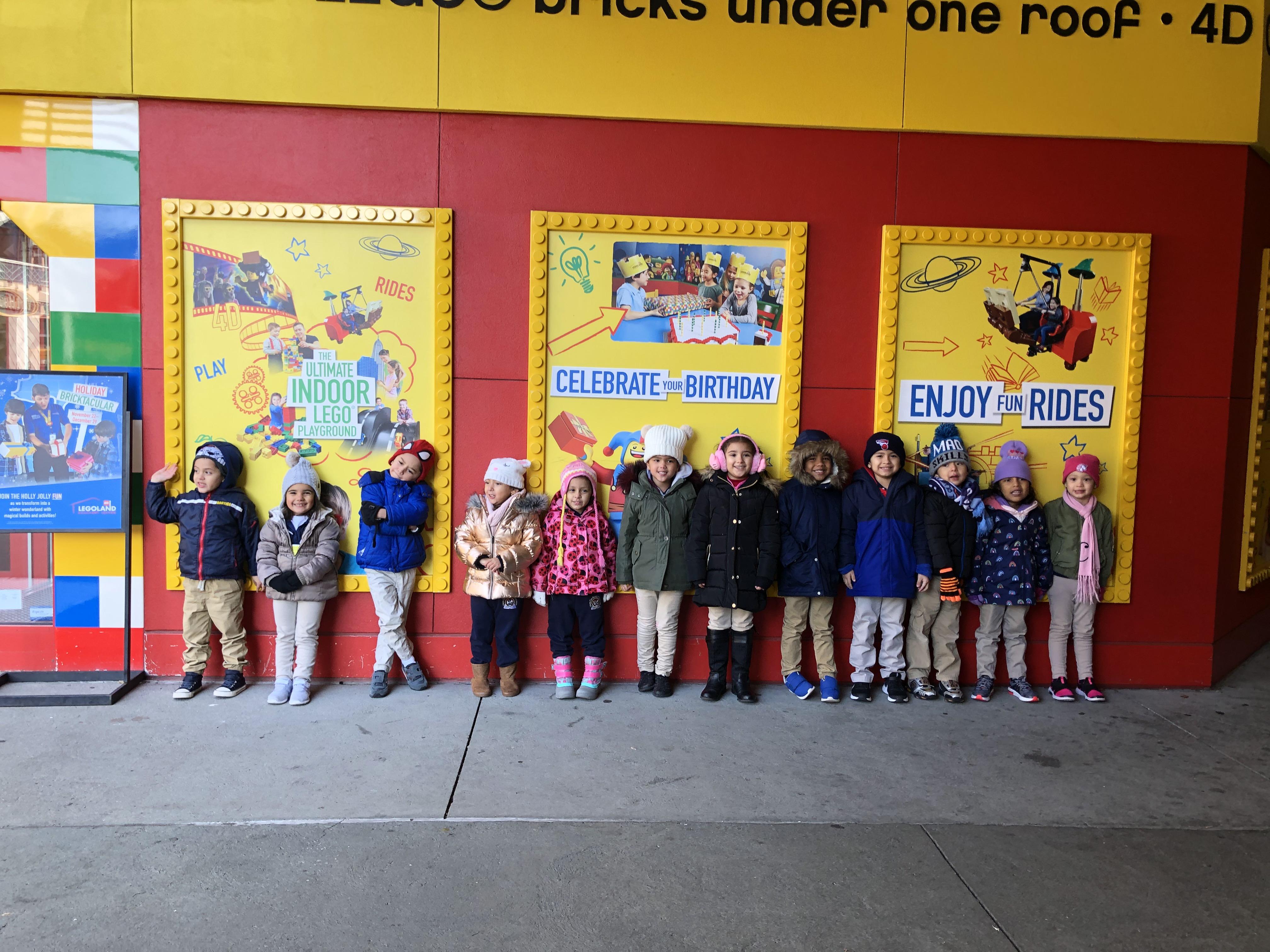 the children standing against the entryway of the legoland in casual poses