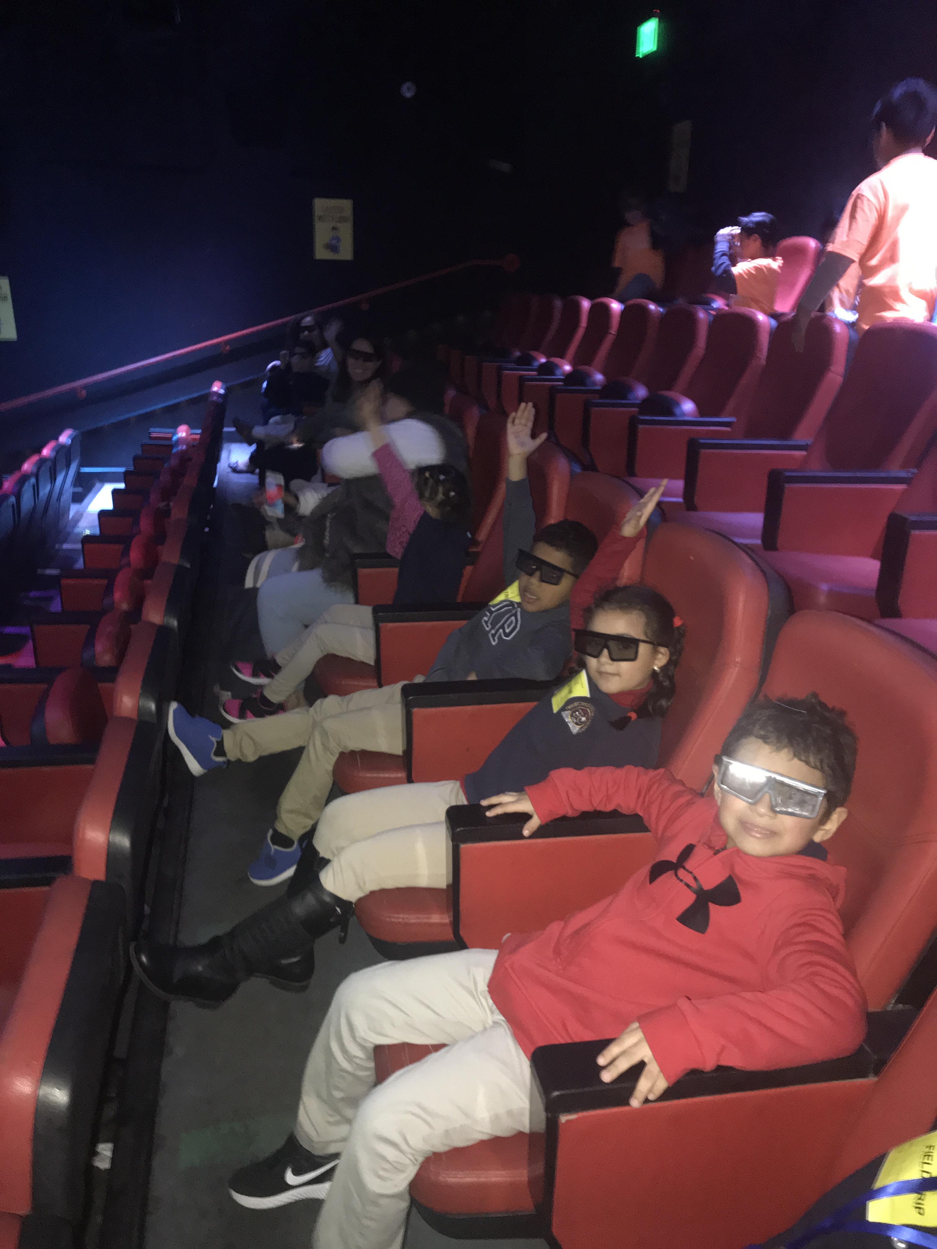 the students with 3d glasses in the theater smiling