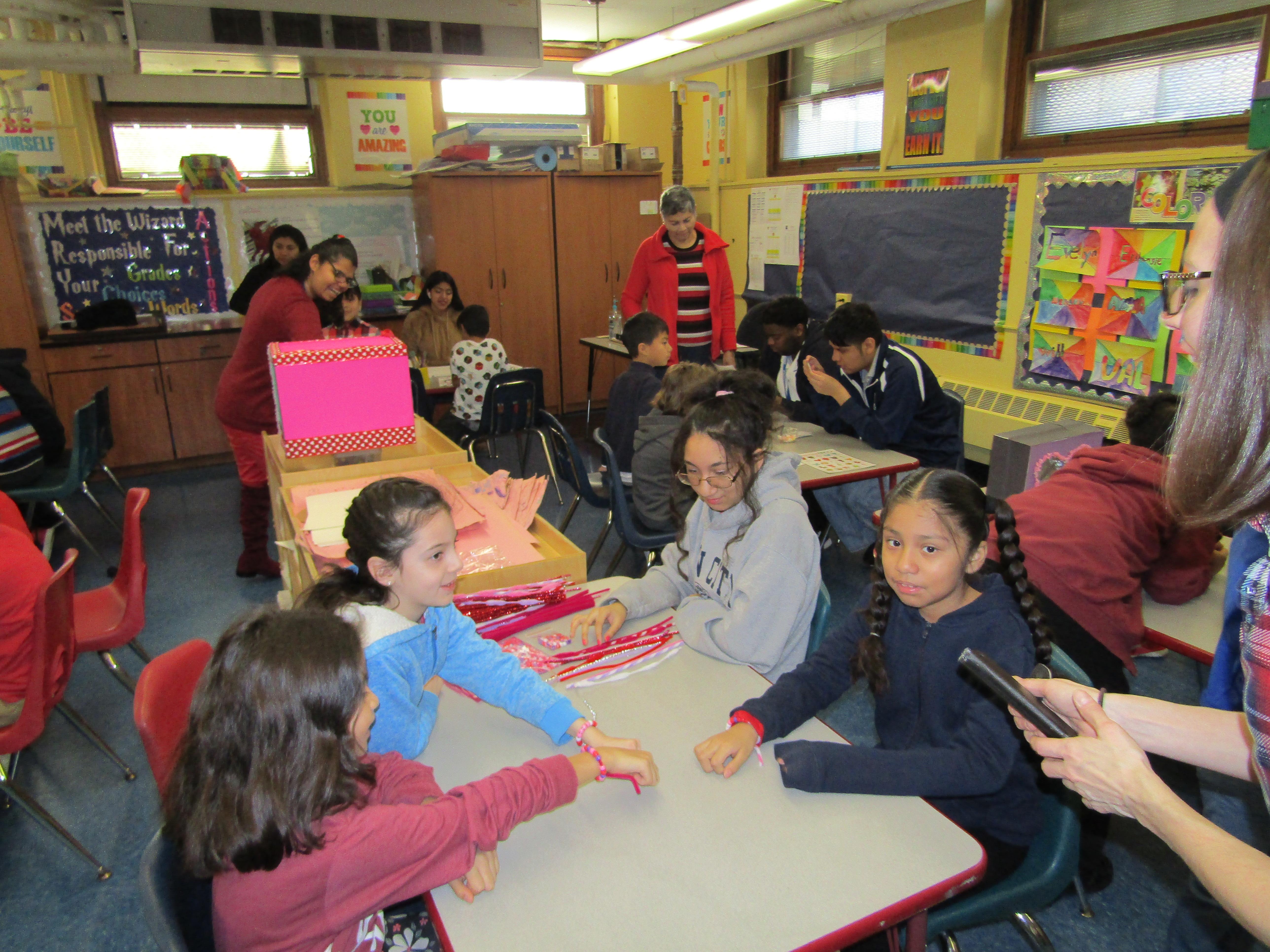 group of girls making bracelets with red, pink and purple string
