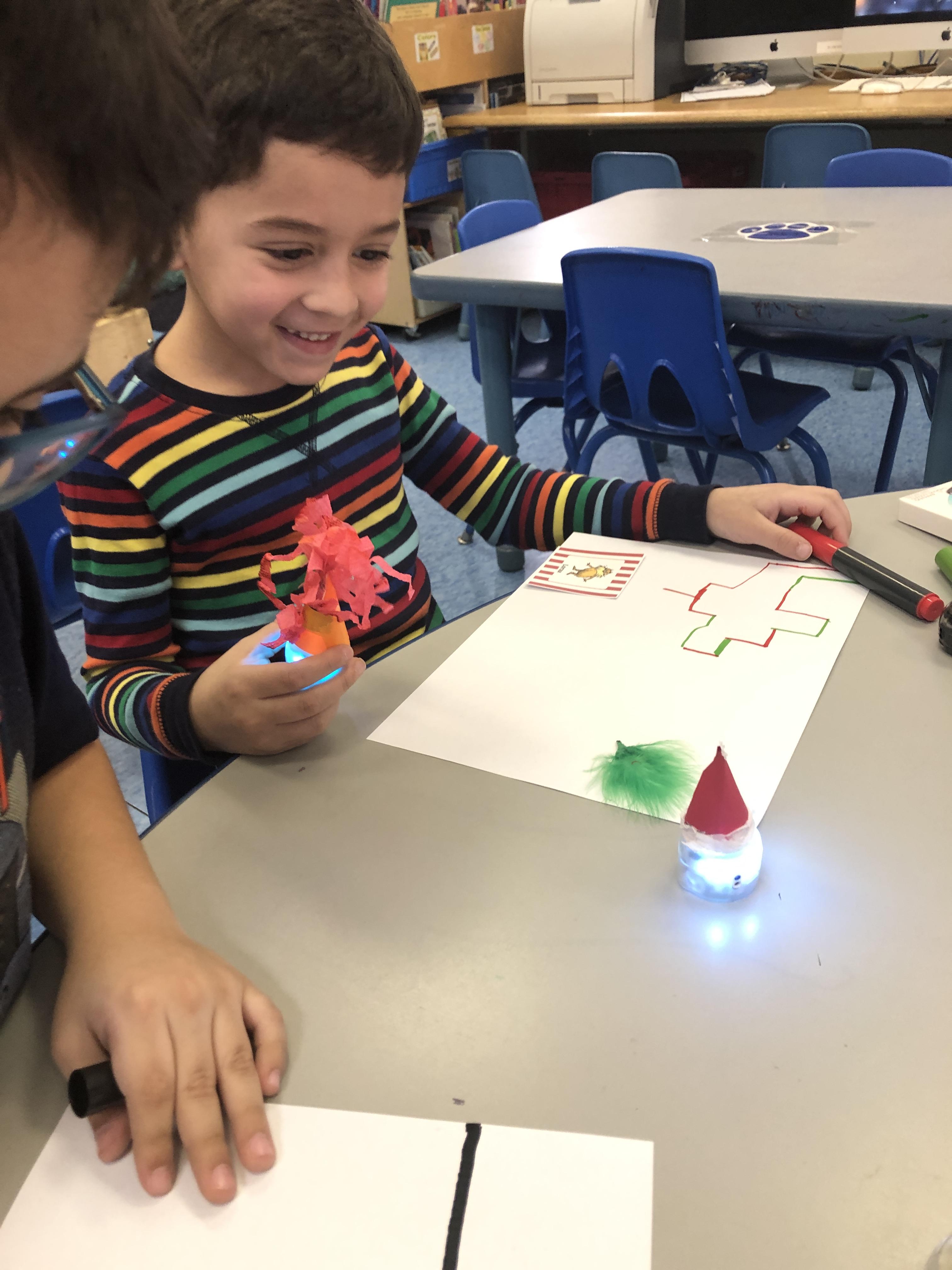  little boy holding ozobot in his hand as he plans its path