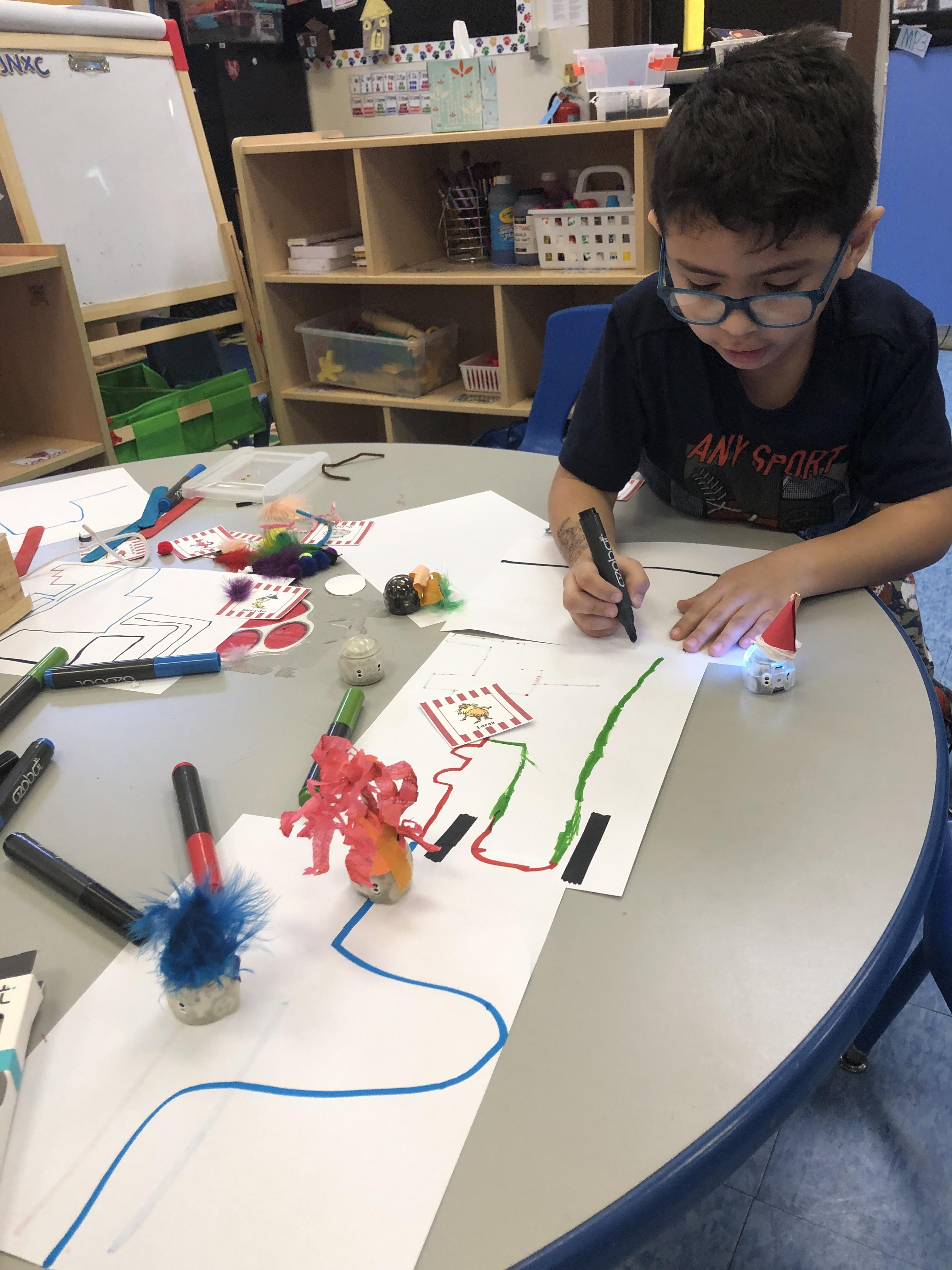 boy with glasses making corrections to the ozobot path he created