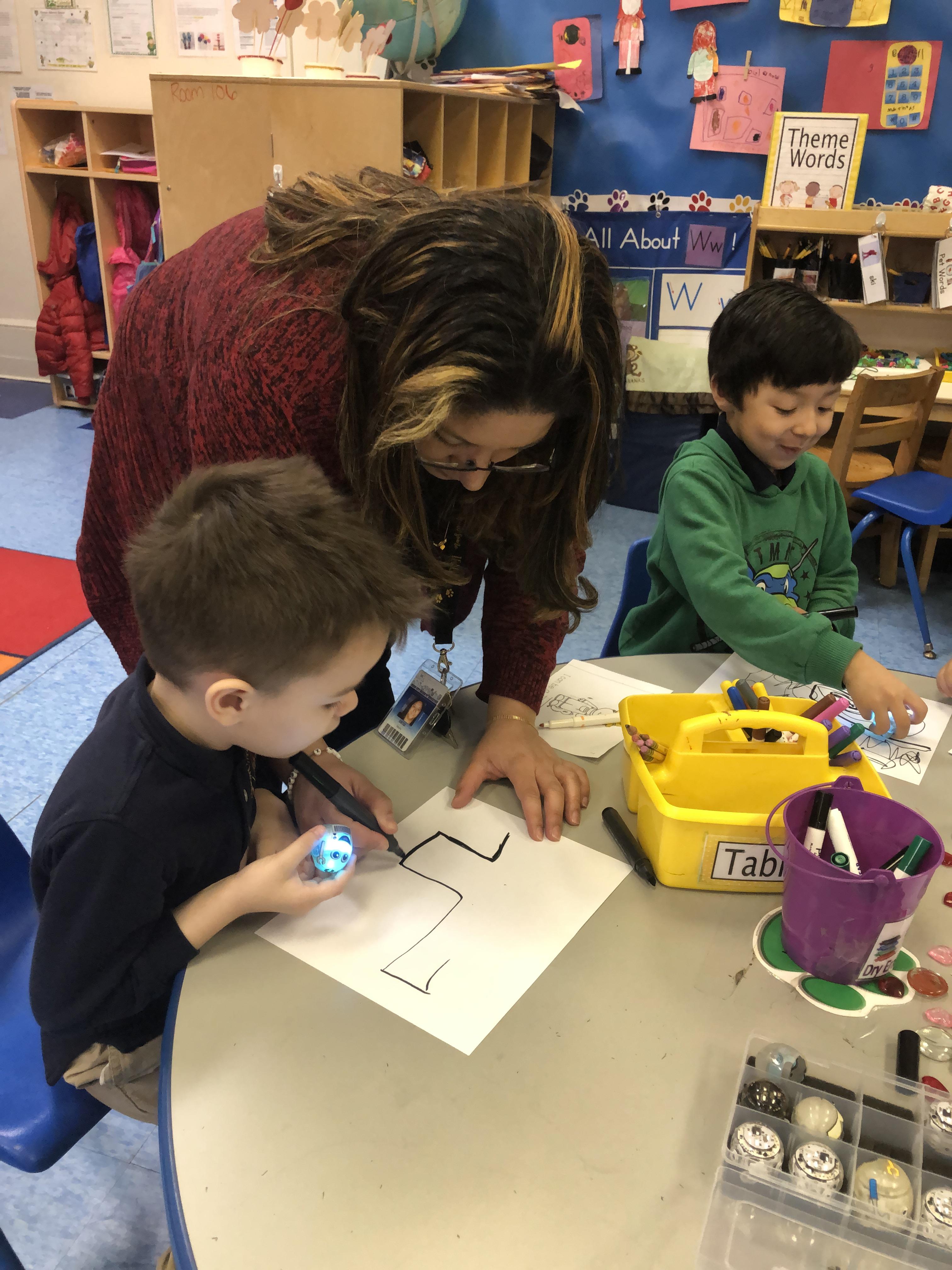 Ms. Ortiz drawing a code line with a two boys 