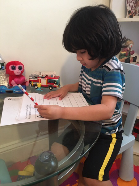 little boy at his table doing his work