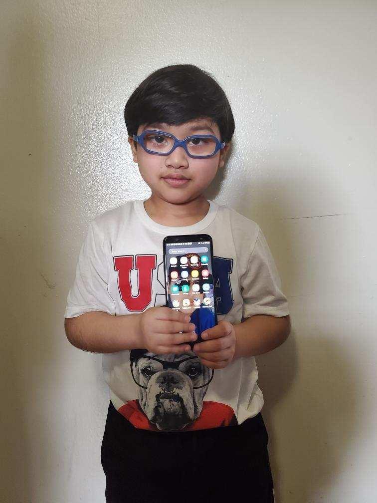 boy with glasses holding up a cell phone