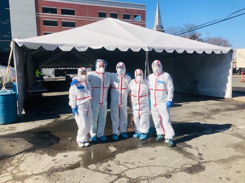 nurses in hazmat suits in front of testing tent for covid